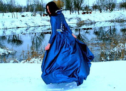 woman swaying her royal-blue gown on snow