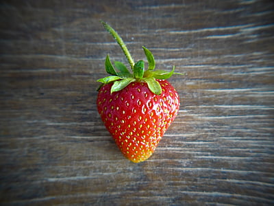 close-up photo of red strawberry on brown wooden surface