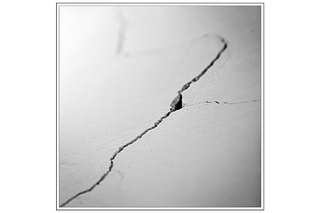 grayscale photo of cracked concrete wall