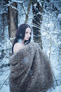 woman wearing brown fur coat standing near snow covered ground and trees