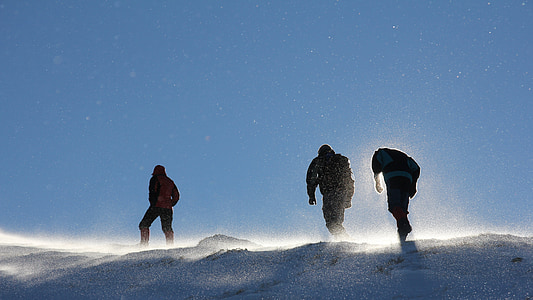 low angle of three men climbing snowy mountain