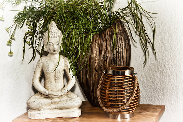 gautama Buddha figurine near brown wooden vase