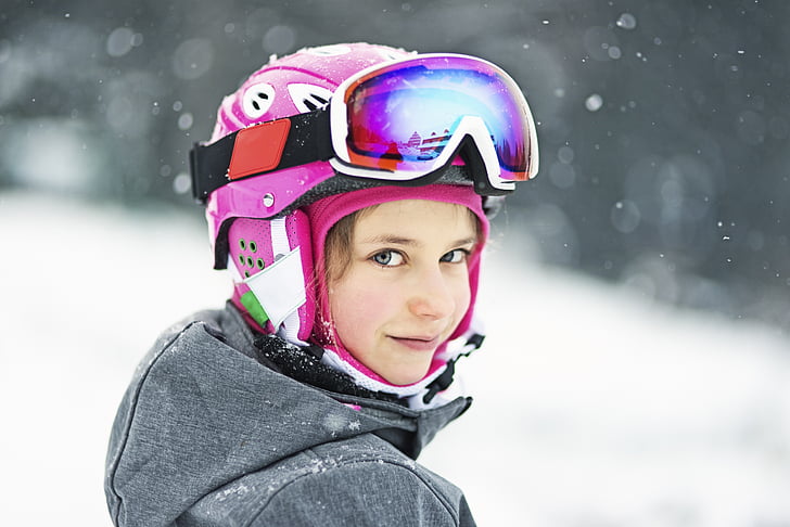 girl wearing pink helmet and snow goggles