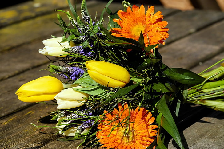 yellow and orange petaled flower bouquet on brown wooden surface