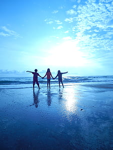 three children on the shoreline during daytime