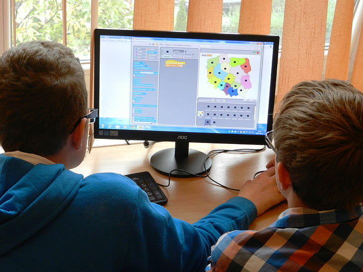 two boy playing computer beside clear glass window