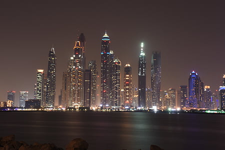 city buildings near body of water during night time