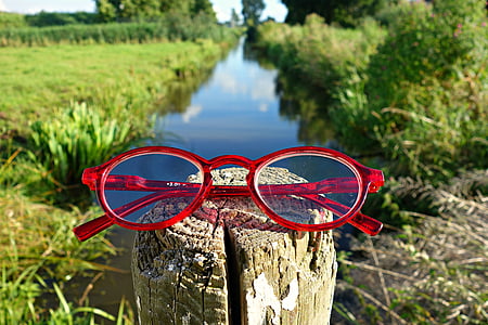 red framed eyeglasses on wooden trunk