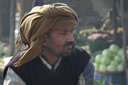 man in brown turban headdress and black vest
