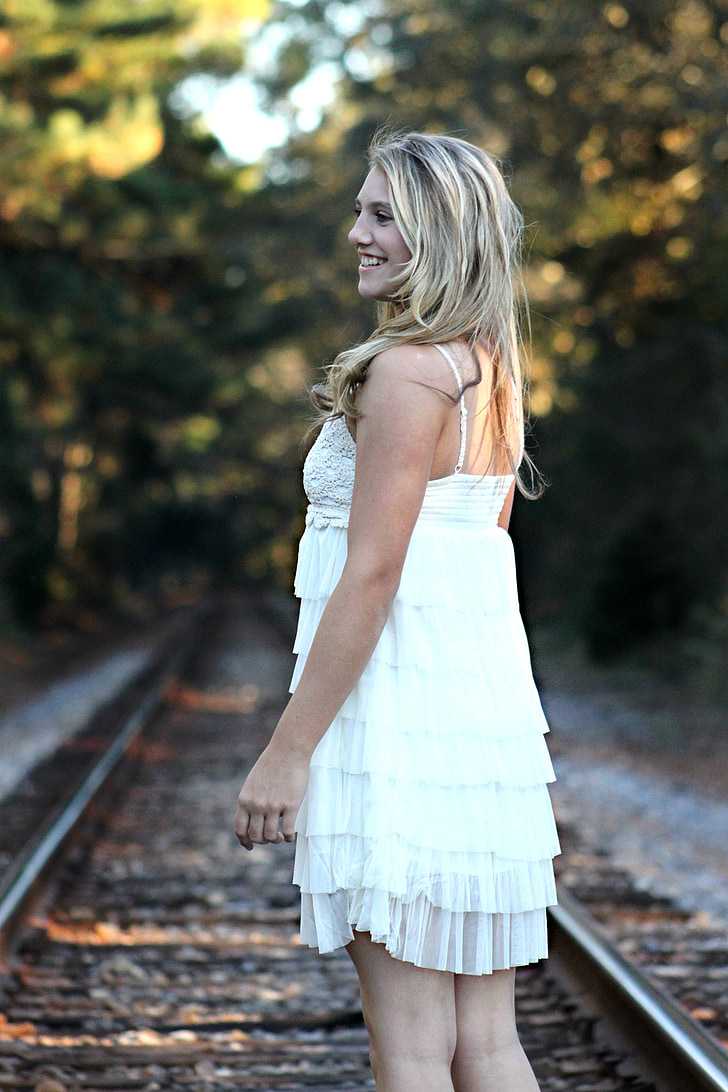 closeup photography of woman standing on train rail wearing white spaghetti strap dress