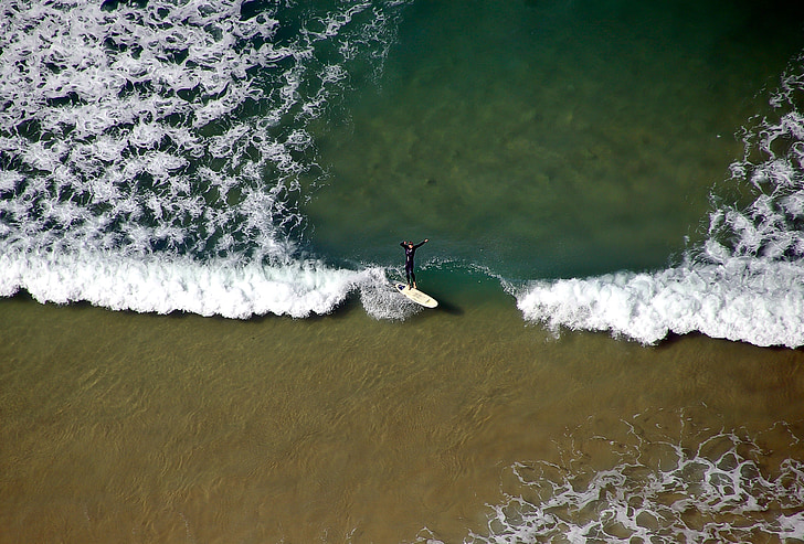 aerial photo of person surfing on beach during daytime
