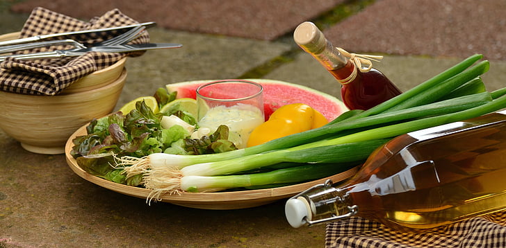 vegetables and fruits on brown plate near brown bowl and clear glass bottles