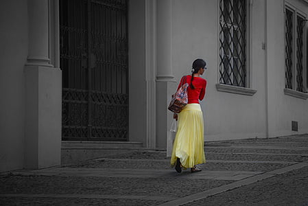 selective color of woman in red long-sleeved top and yellow skirt walking on near building
