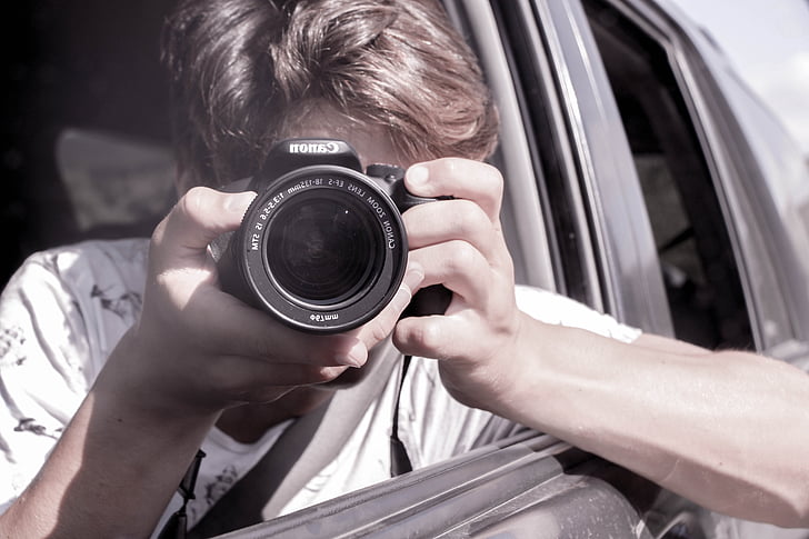 person holding DSLR camera inside car during daytime