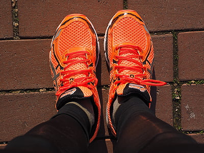 closeup photo of person wearing orange-and-black running shoes