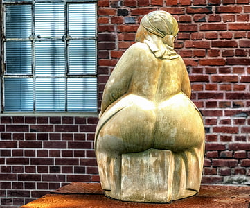 sitting woman statuette near windowpane