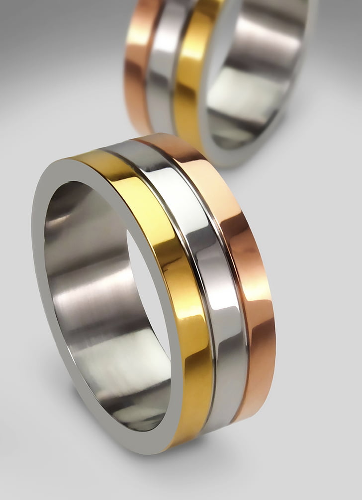 two gold-and-silver-colored rings on white panel