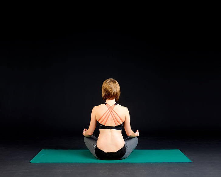 woman in black sports bra sitting on green yoga mat