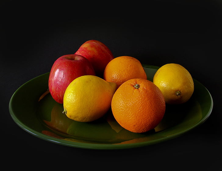 four orange fruits and two honeycrisp apple fruits on clear glass plate