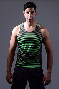 man wearing black and green striped tank top and gray bottoms standing