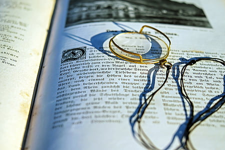gold-colored framed eyeglass on top of book