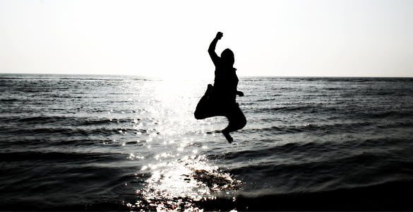 silhouette of person jumping on body of water