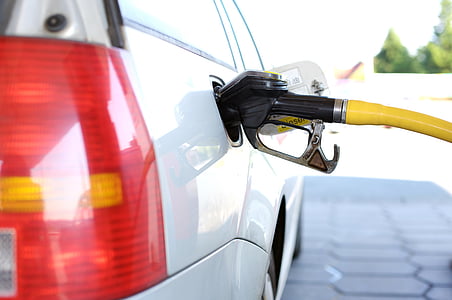 white vehicle filling gas tank using gasoline pump
