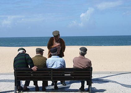 man standing infront of four men sitting on bench during daytime