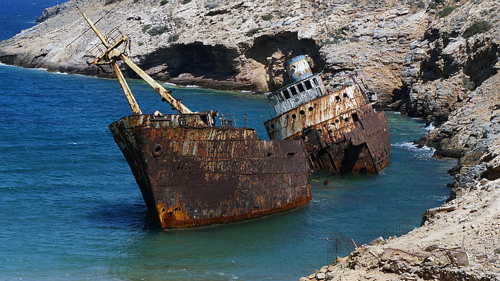 corroded shipwreck docked on body of water