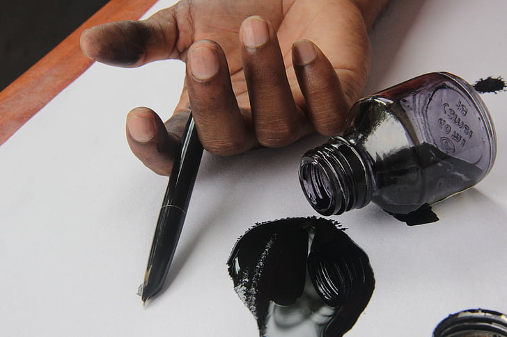 person holding fountain pen and ink