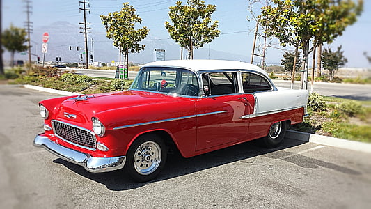 classic red and white coupe park near green leaf tree