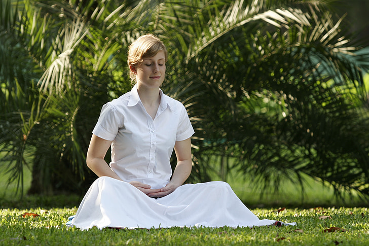 woman in white shirt and skirt sitting on grass lawn