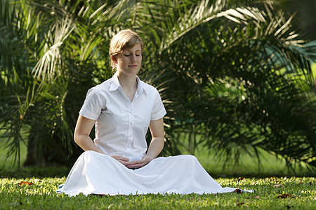 woman in white shirt and skirt sitting on grass lawn