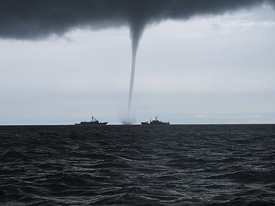 two black ship at sea near tornado