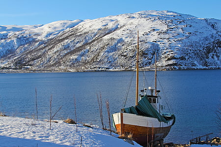 brown and white boat near the snowy mountain