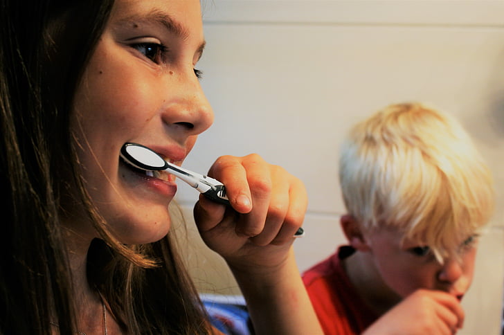 photo of girl and boy holding toothbrushes