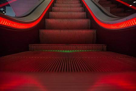 close photography of red lighted escalator