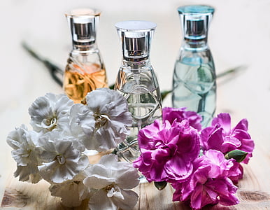 selective focus photography of three spray bottles behind pink and white petaled flowers