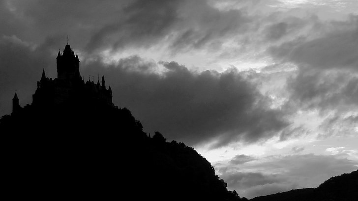 silhouette of castle on top of mountain under cloudy sky