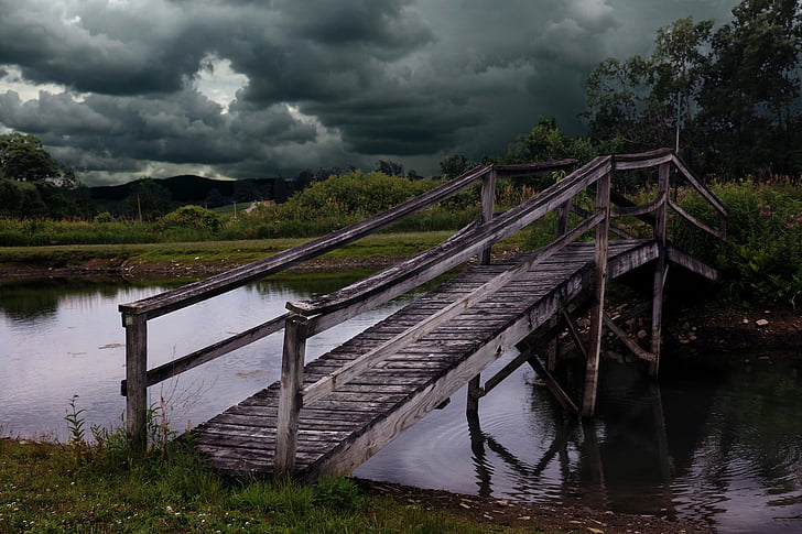 gray wooden bridge under gray clouds during daytime