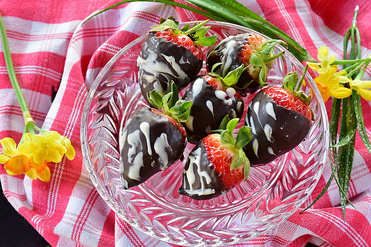 chocolate coated strawberries on clear cut glass bowl
