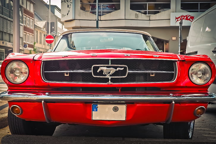 red Ford Mustang Fastback parked on gray road