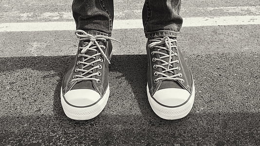 grayscale photo of person wearing low-top shoes