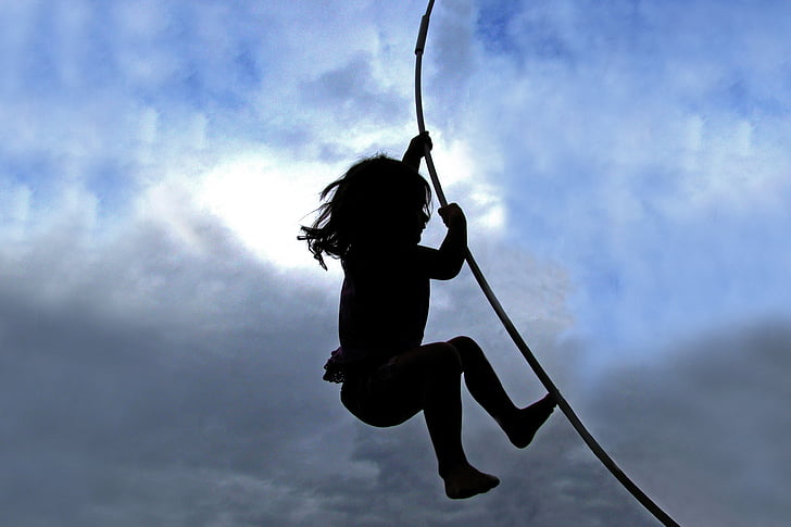 silhouette of child holding on rope