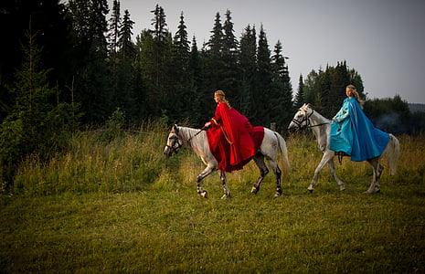 two woman riding on white horses