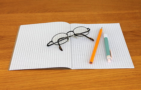 eyeglasses on paper near pencil