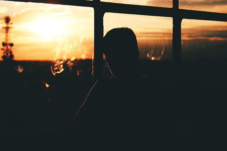 silhouette of man sitting near glass window