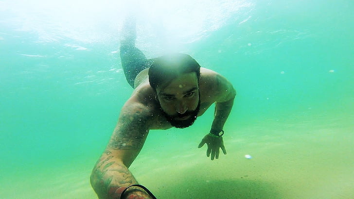 man swimming in body of water during daytime