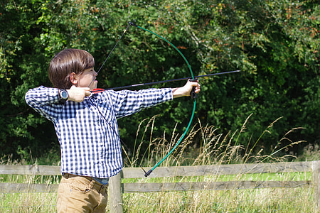 boy in blue and white checked sport shirt holding crossbow