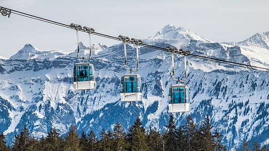photo of three cable car near snow covered mountains during daytime